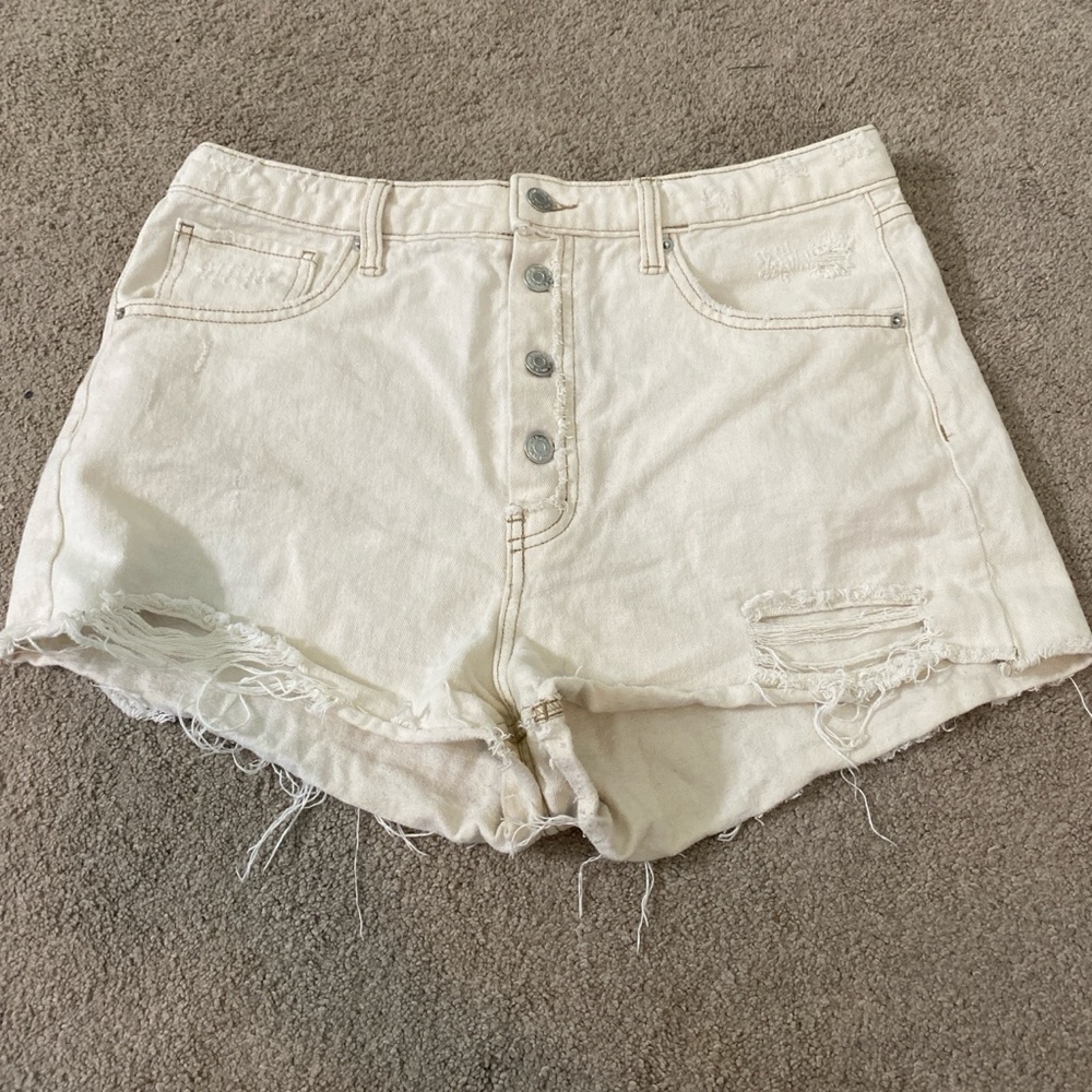 A high waisted tannish cream colored ripped jeans shorts